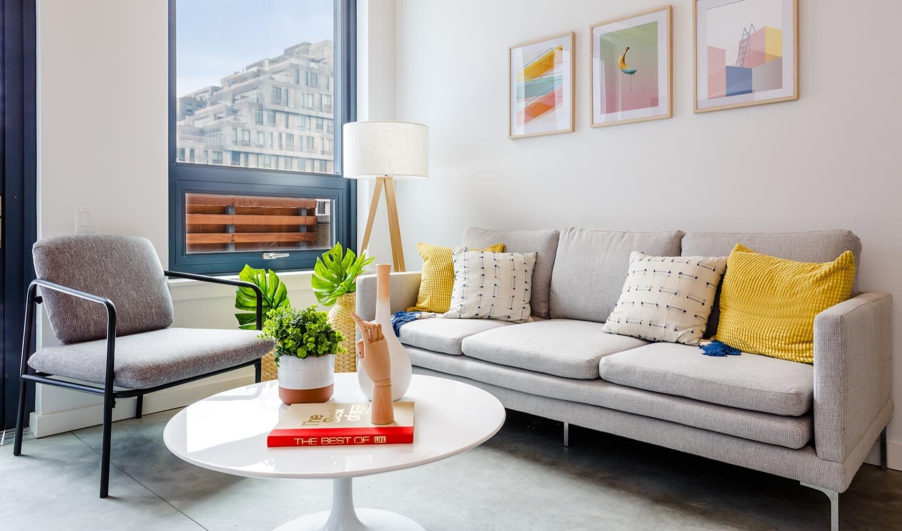 a living room with a white couch and a table with a lamp